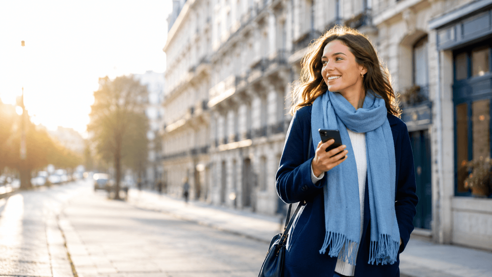 Jeune femme souriante marchant dans une rue parisienne, smartphone à la main